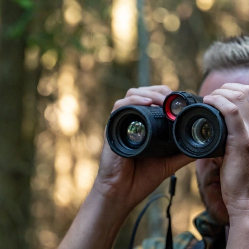 Cazador observando a través de los binoculares NOCPIX OMNI en el bosque
