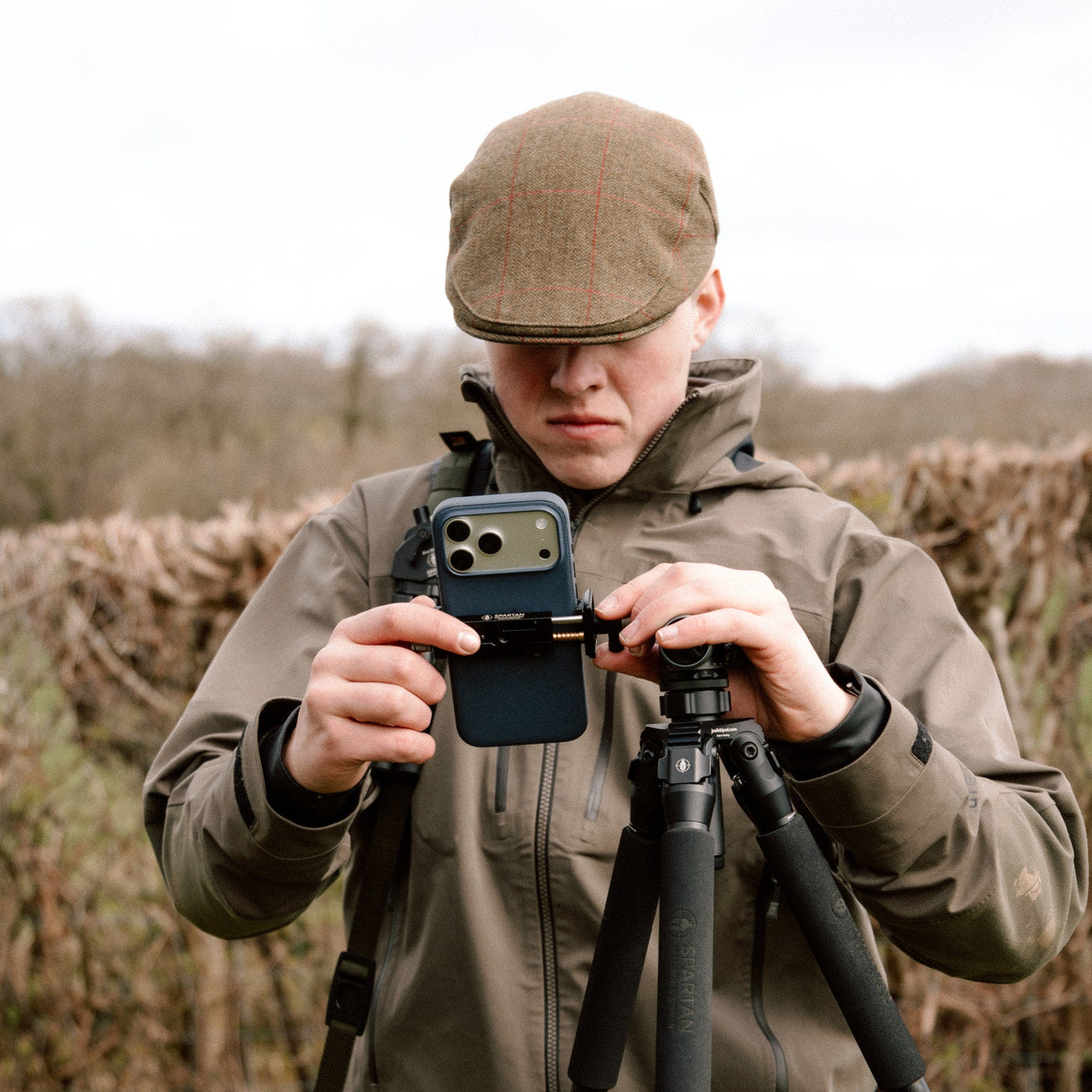 Cazador con un smartphone en el Spartan Phone Holder sobre trípode